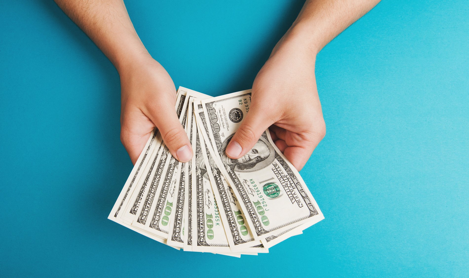 person holding hundred dollar bills getty images
