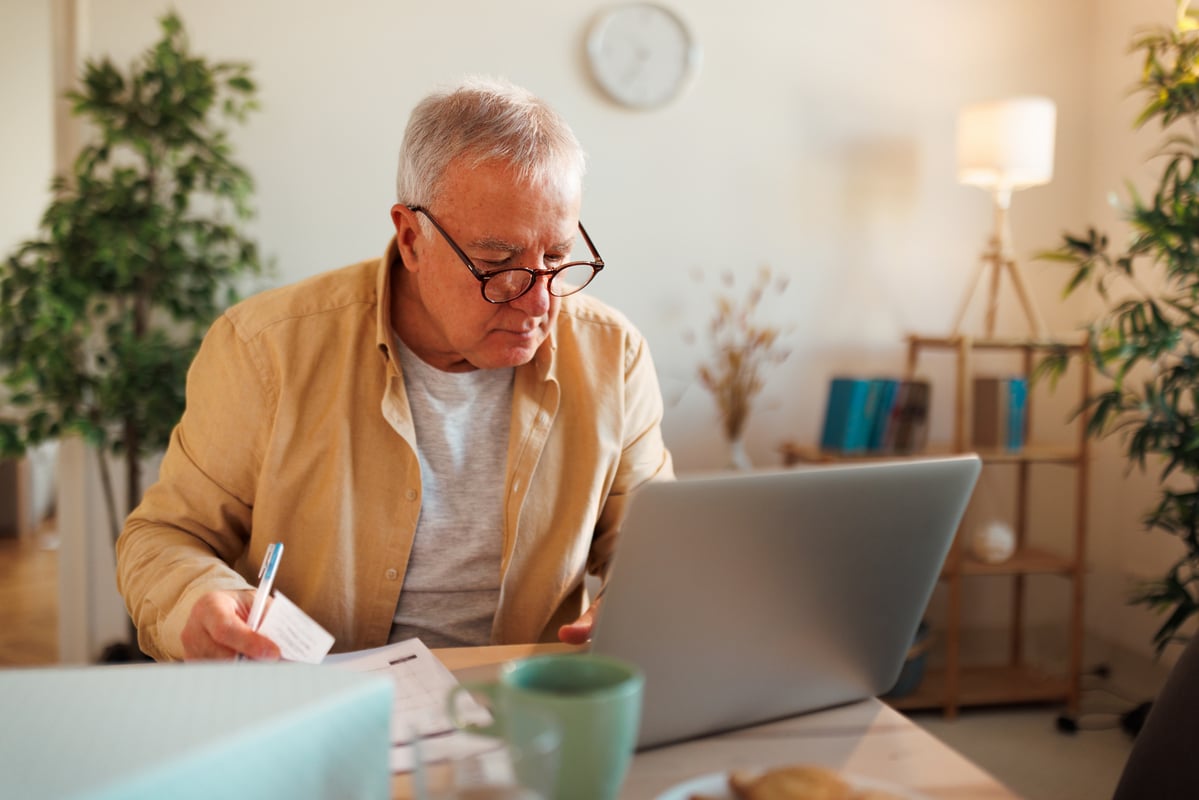 Person holding paper and looking at laptop