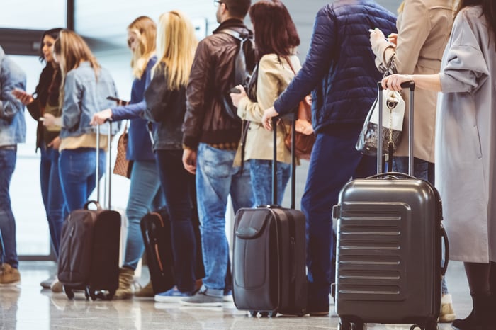 Travelers in line with their luggage getting ready to board an airplane. 