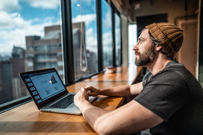 A person at a laptop looking out a window.