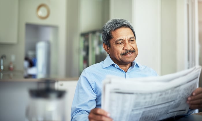 Someone sitting down and reading a newspaper.