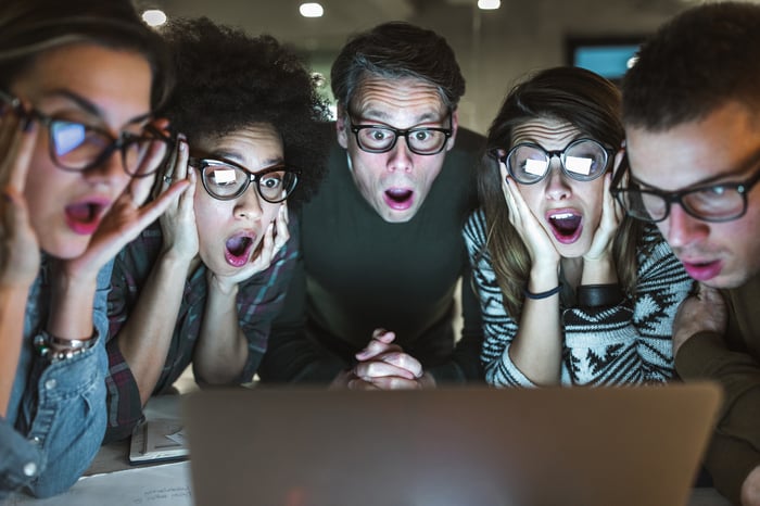 Group of people looking at a laptop with surprised expression.