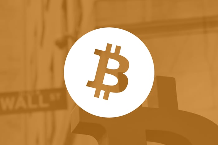 The Bitcoin logo over a shadowy dark yellow background.