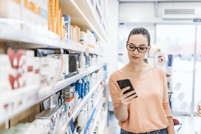A person is looking at a smartphone while shopping in a store.