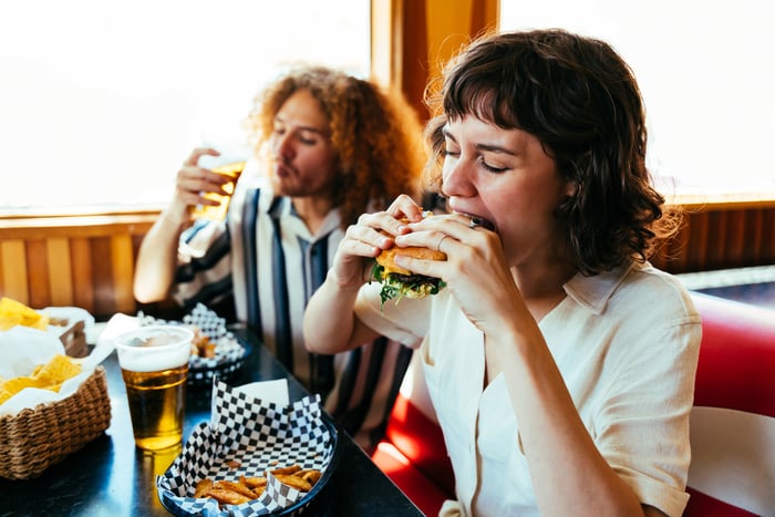 People sitting in a restaurant eating burgers.