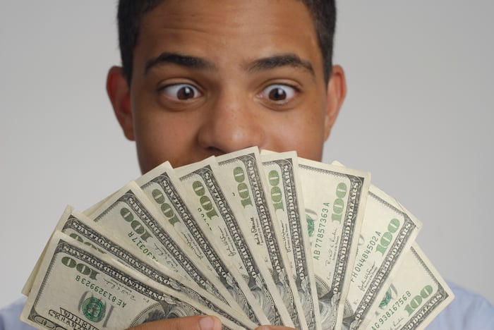 Person looking at and holding $1,000 in cash in 10 $100 bills.