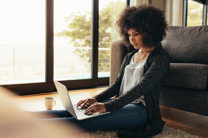 Person sitting on floor is using laptop.