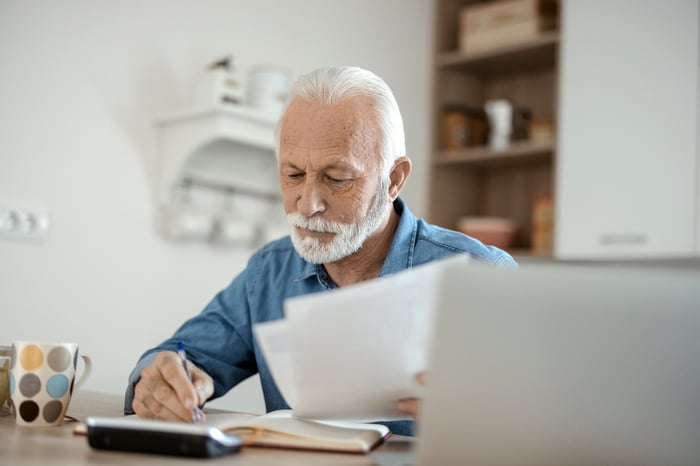 A person seated and holding papers.