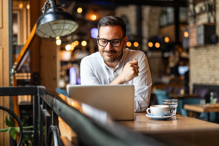 happy investor works on laptop in cafe.