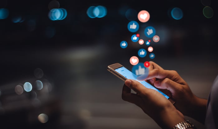 Social media icons floating up from a smartphone.