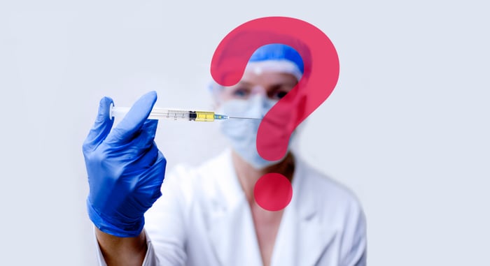 A question mark in front of a person wearing a mask and blue gloves holding a syringe.