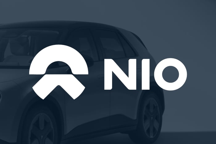 white Nio logo set over dark shaded picture of one of its EVs.