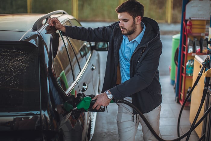 An individual pumps gas at a gas station.