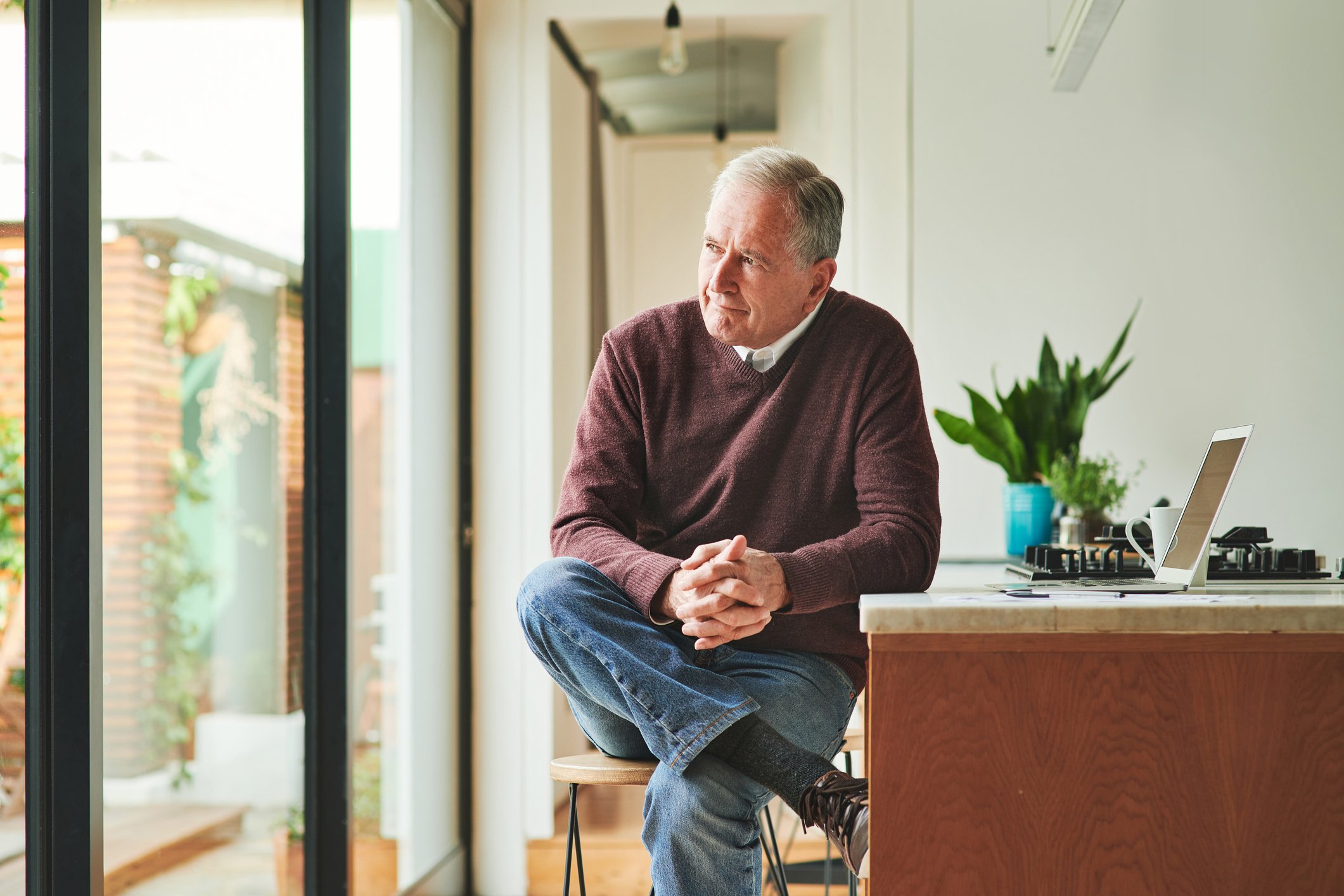 Older man looking out window_GettyImages-1316738445