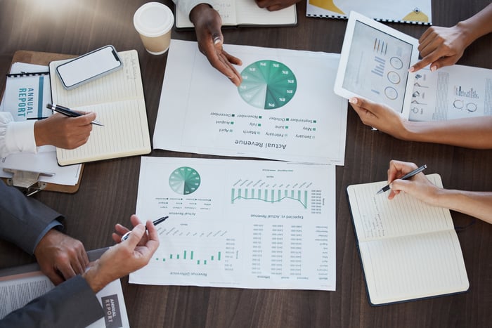 Hands on a desk with charts on papers.