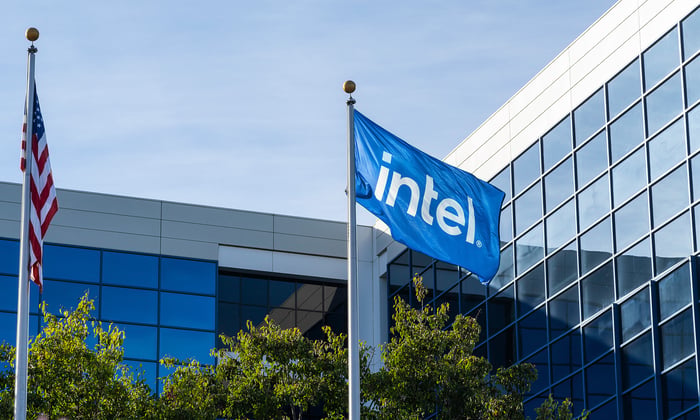 Intel flag flying along with the U.S. flag in front of a modern office building.