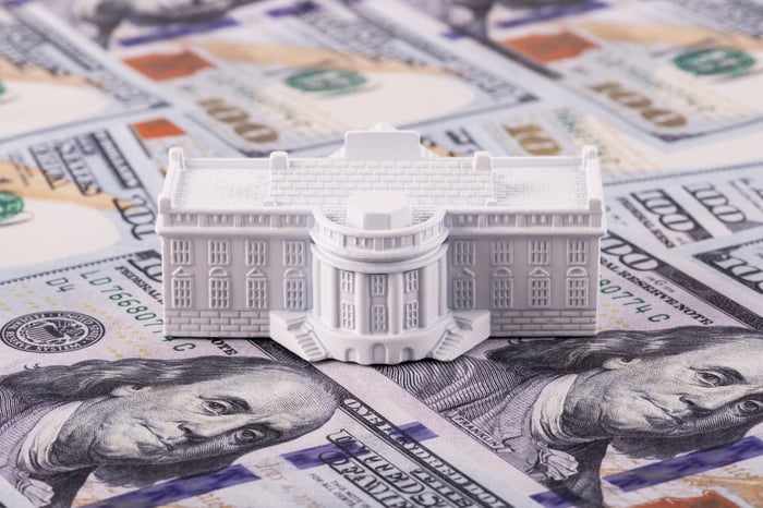 A model of the White House set against hundred-dollar bills shows the idea of how presidents affect the stock market.