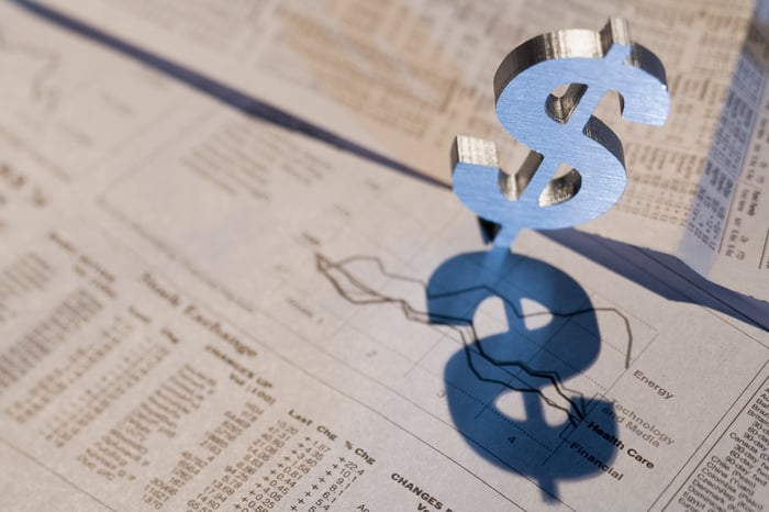 A dollar sign on papers featuring charts and information.