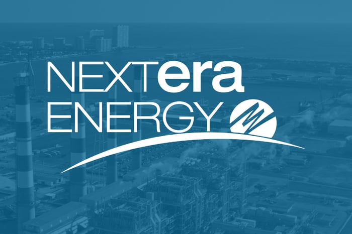 A white NextEra Energy logo set over a blue shaded aerial view of power plant.