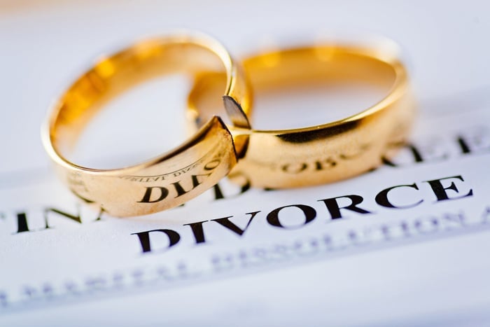 Two gold wedding rings sitting atop a divorce decree. 