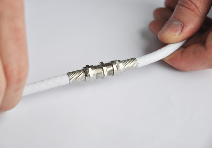 Two hands pushing together coaxial cable connectors.