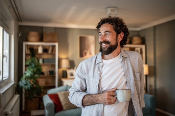 Person in living room, holding mug.
