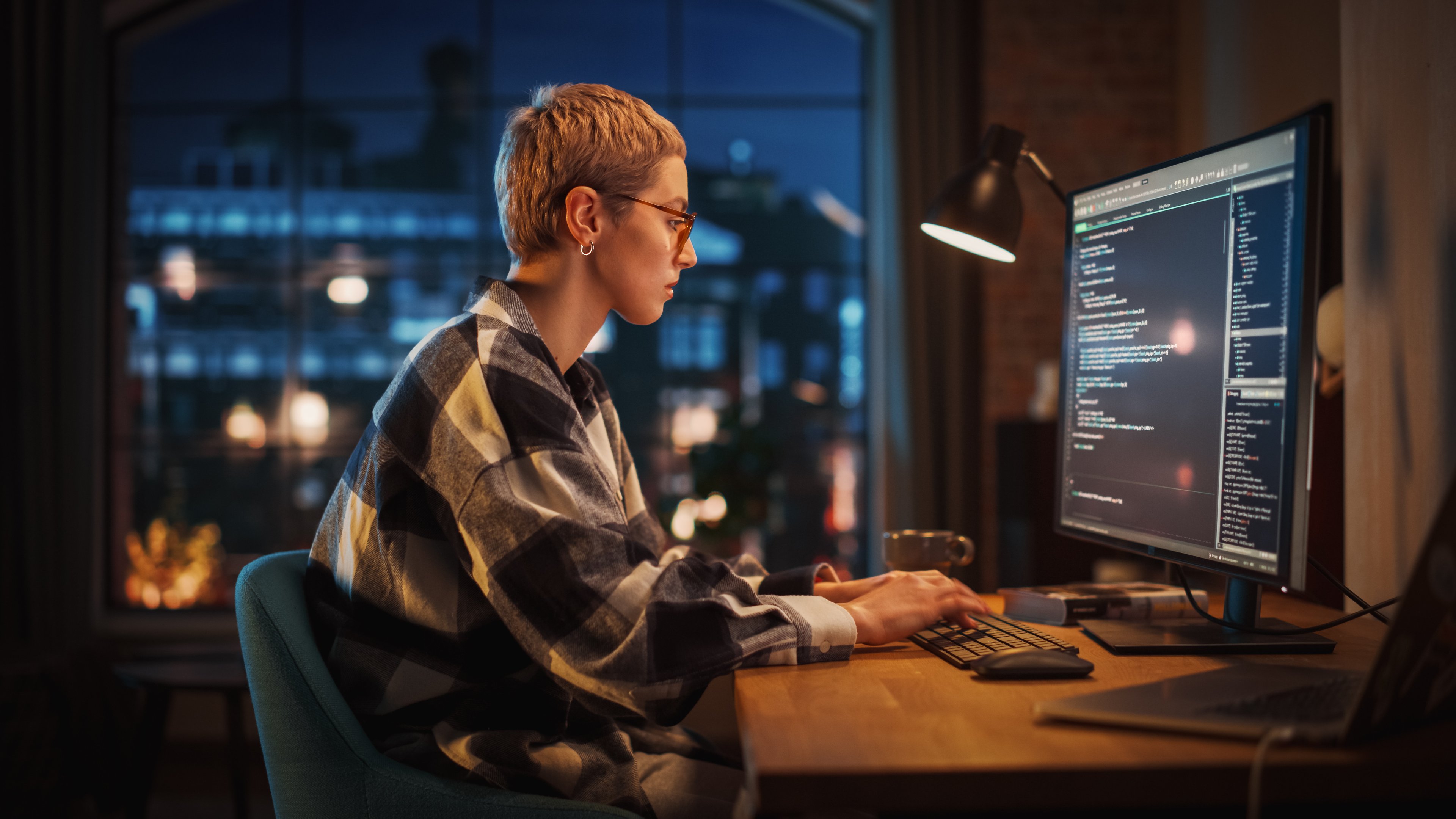 A computer programmer working at a desk in an apartment