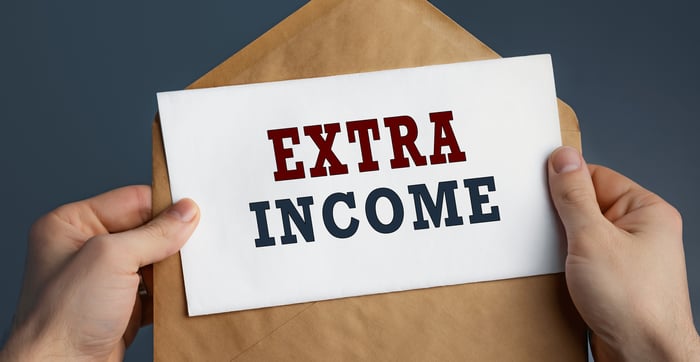 A person holding an envelope and paper that says "extra income."