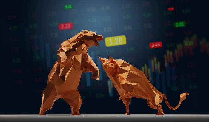A bull and a bear are facing off with stock market figures in the background.