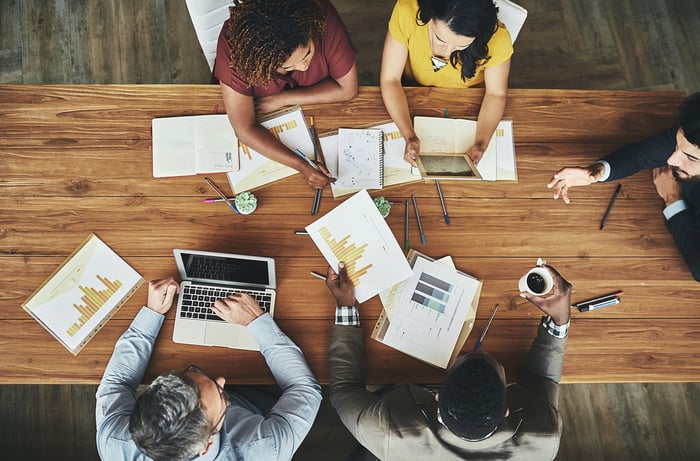 People working at table with documents and laptop.
