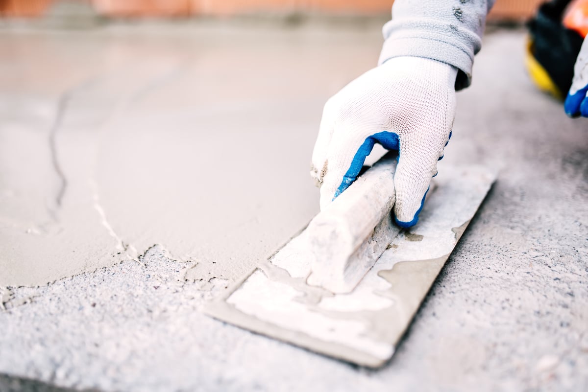 construction worker smoothing beam with a trowel