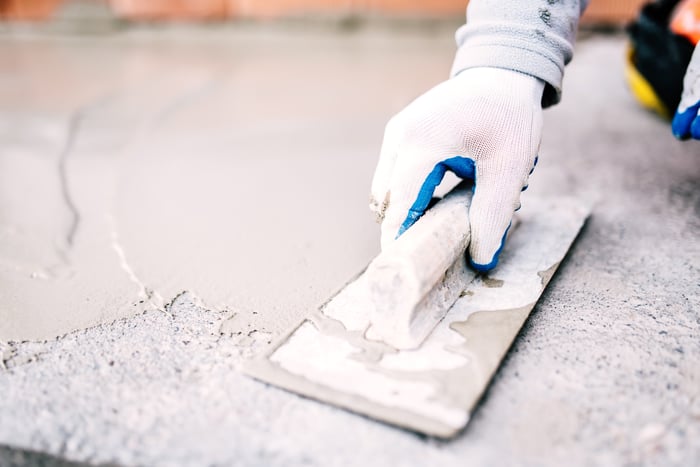 Construction worker smoothing a surface with a trowel.