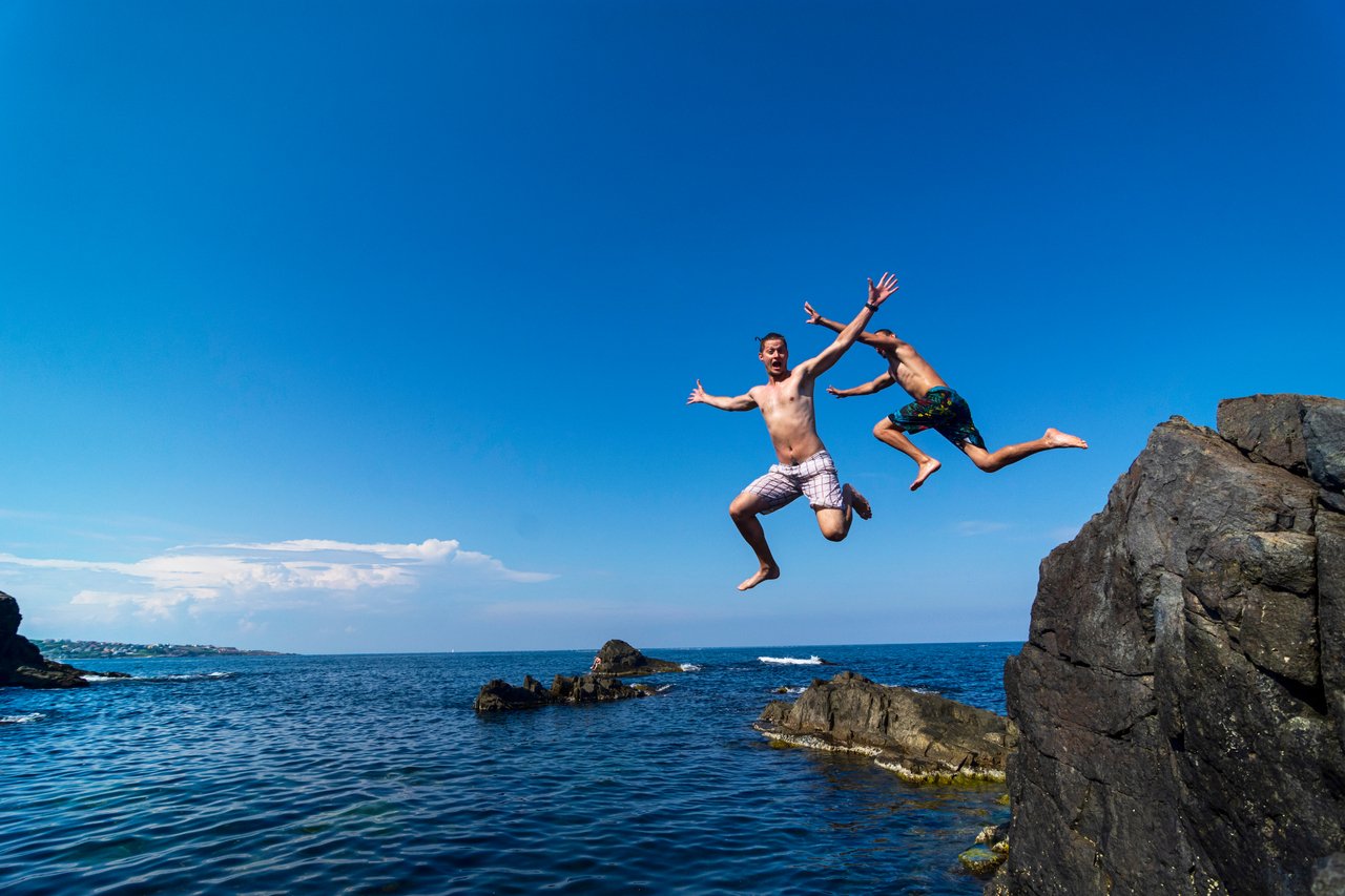 26_10_02 Two people jumping off a cliff into the ocean _MF Dload GettyImages-1211946928-1280x853-c533c3e