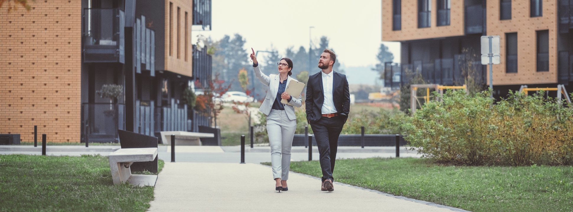 Two people wearing professional attire walking through a real estate development. 2