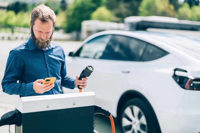 A driver charging an electric vehicle.