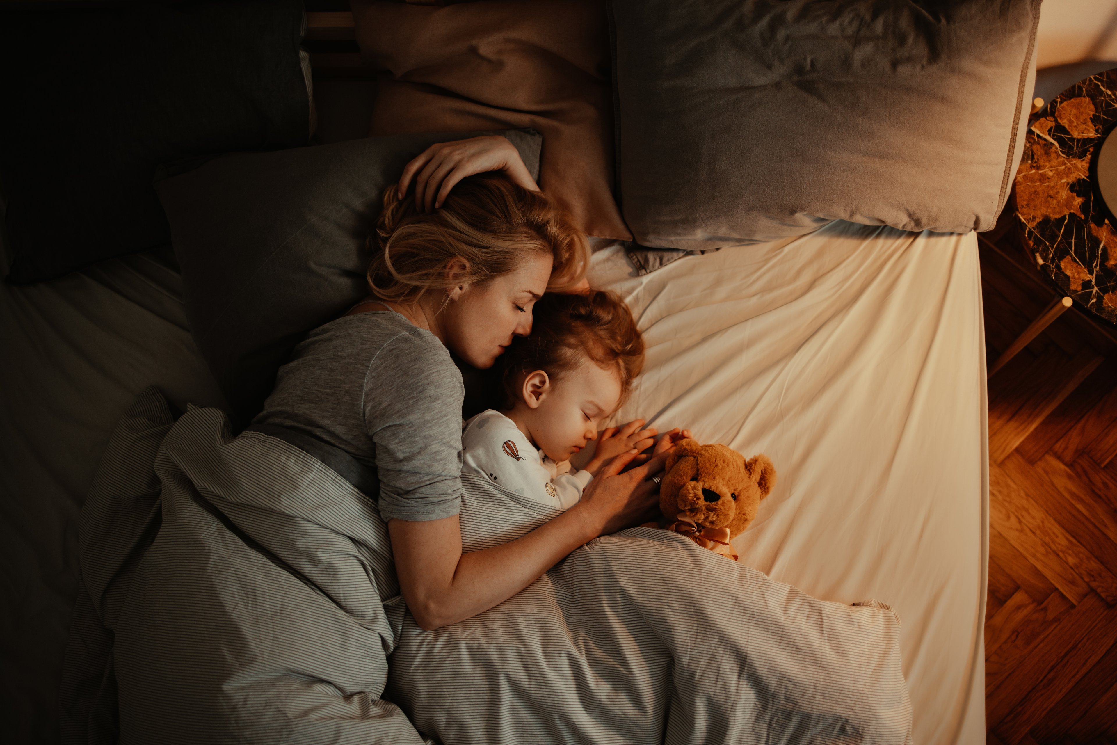 Parent child and stuffed animal lying in bed