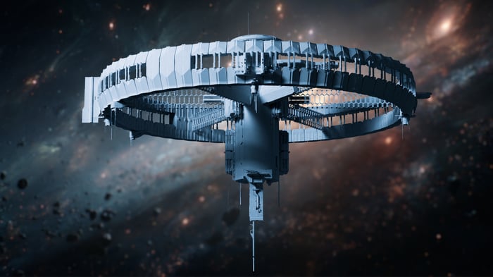 A ring-shaped space station floats among asteroids and distant stars.