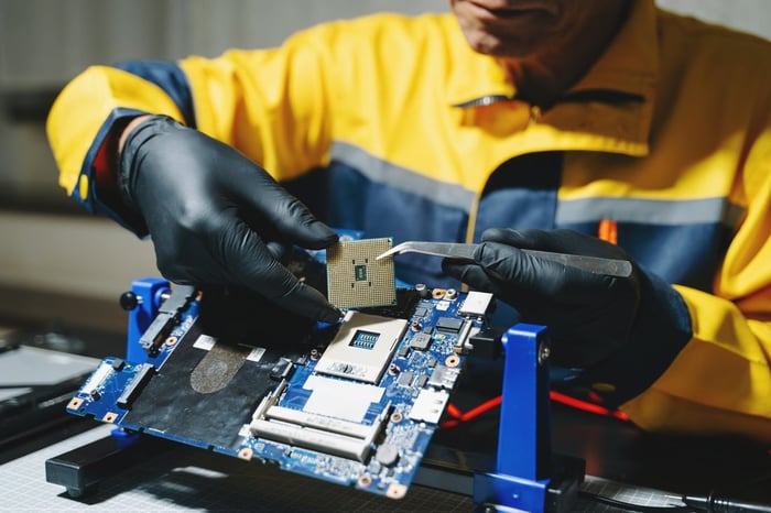 A worker places a large chip into a computer board.