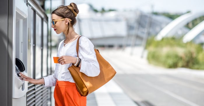 A woman using an ATM on a sunny street.
