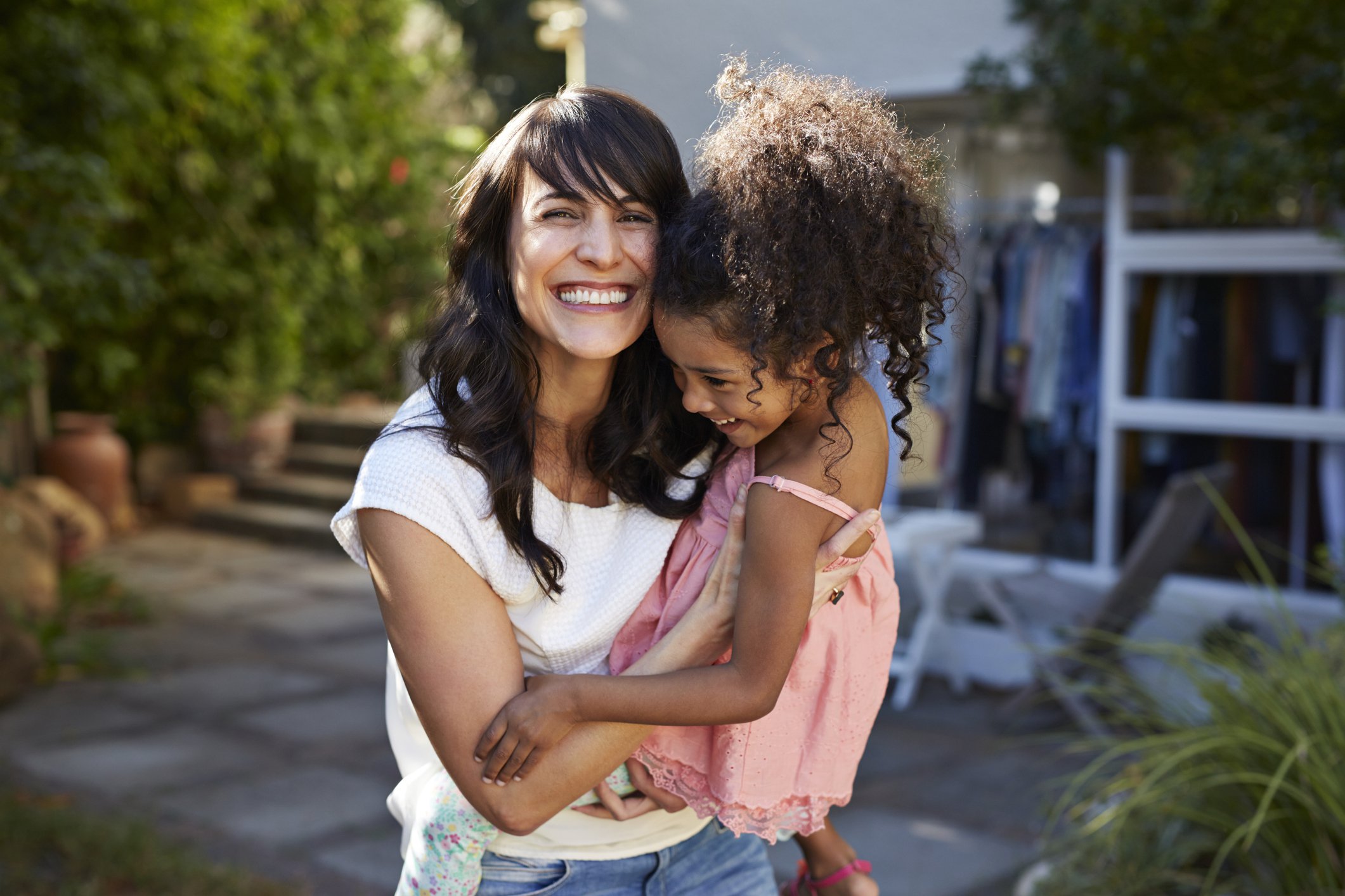 Happy adult holding smiling child on an outdoor patio.