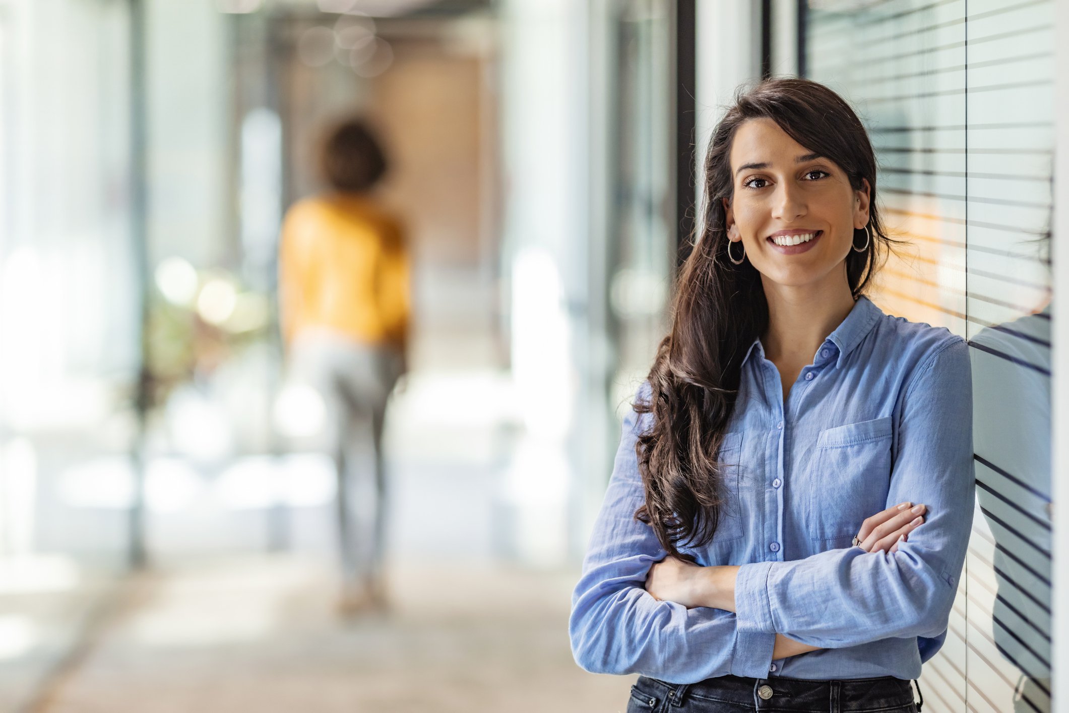 Person smiling and leaning against window in office.