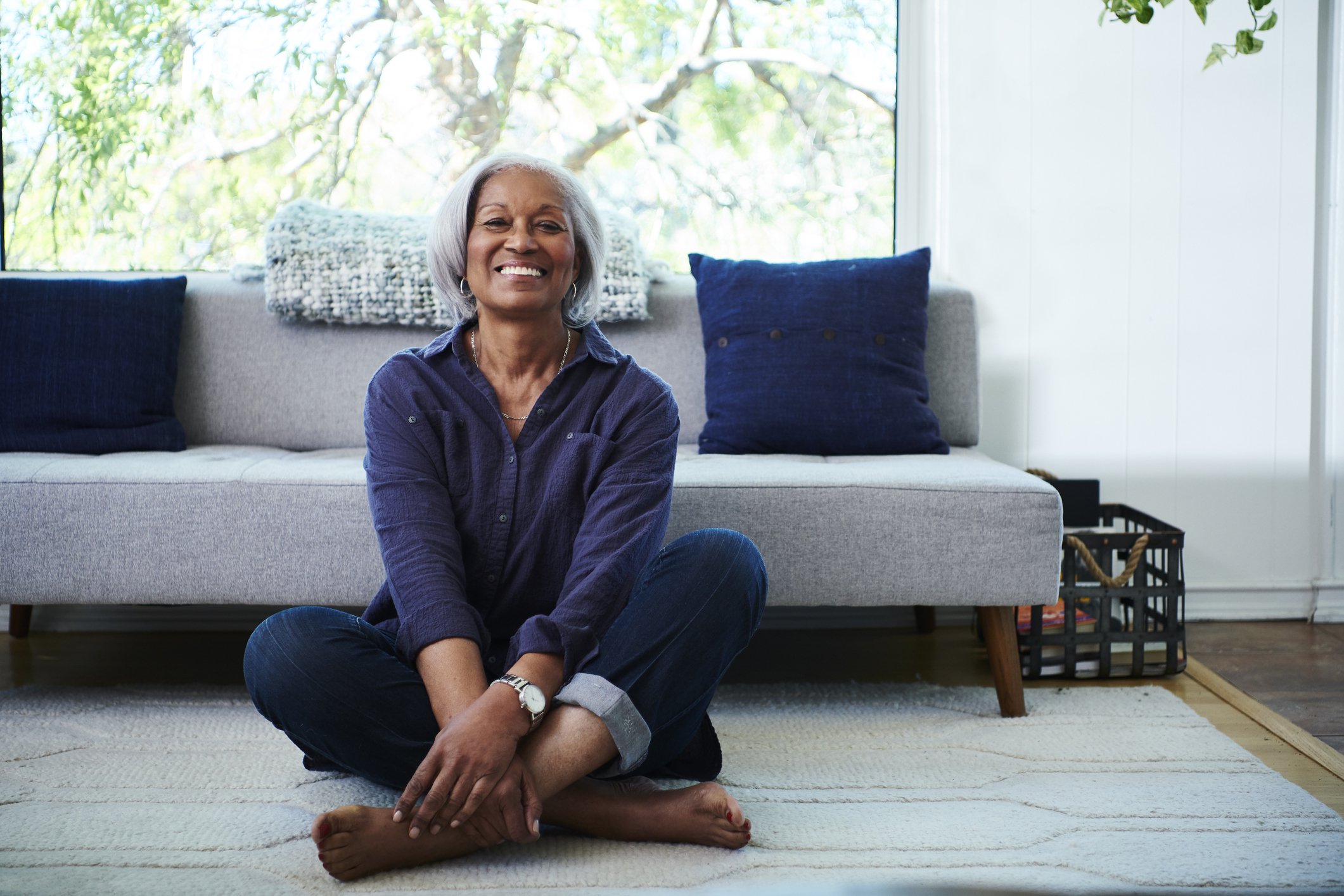 Woman sitting on floor near couch.