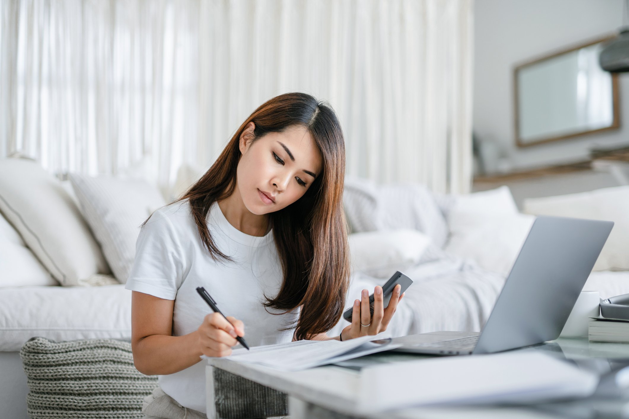 Woman sitting on floor and using coffee table to work and write.