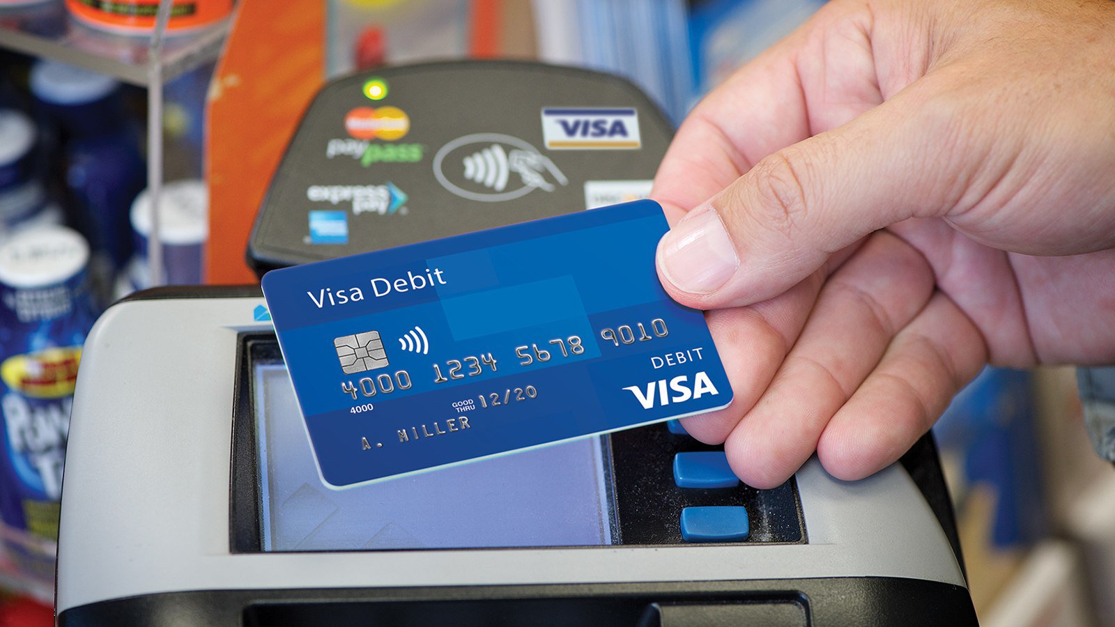 Hand holding a blue Visa card in front of a POS device