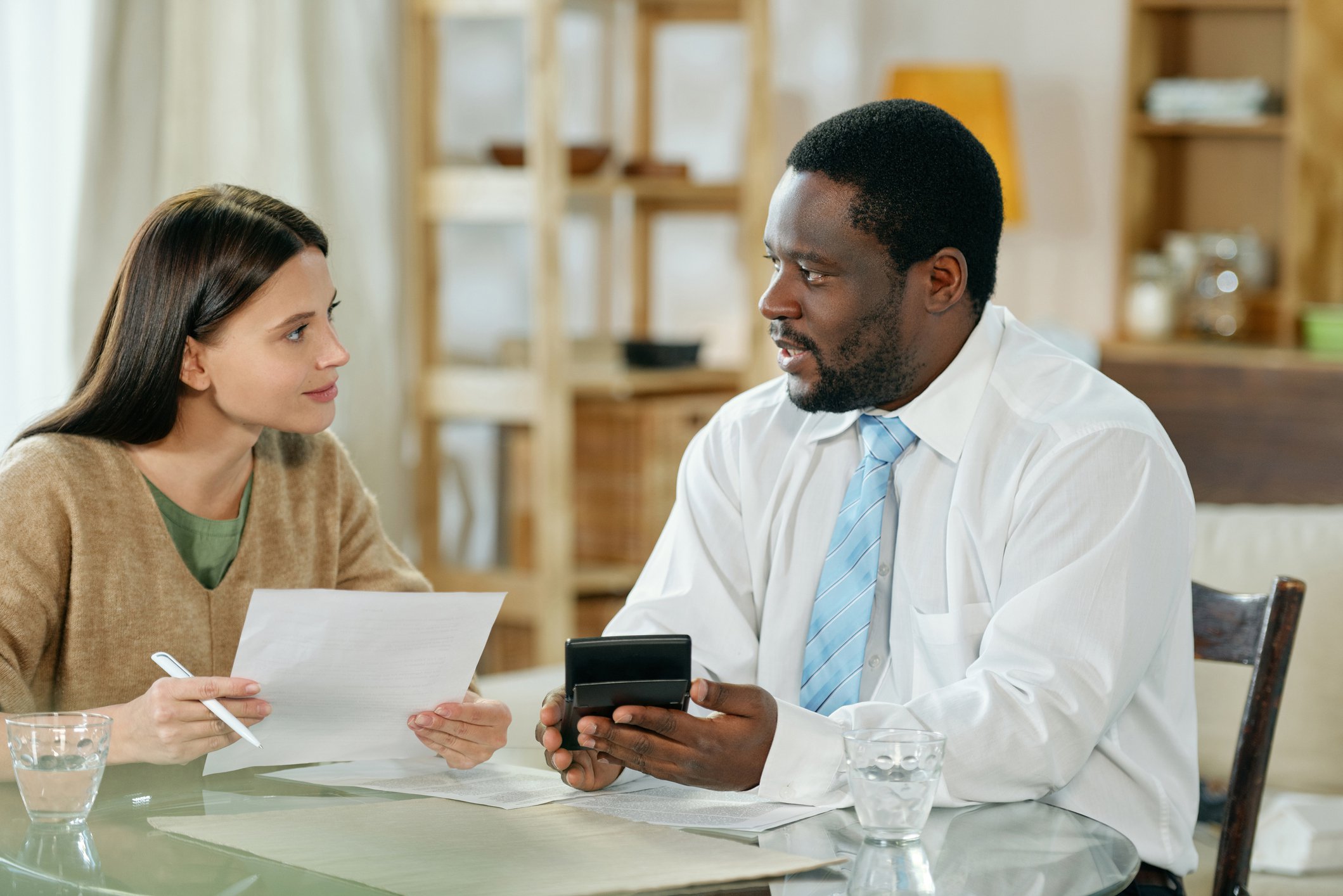 Two people sit at table with calculator and paperwork.