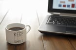 Coffee mug saying Keep Life Simple near laptop