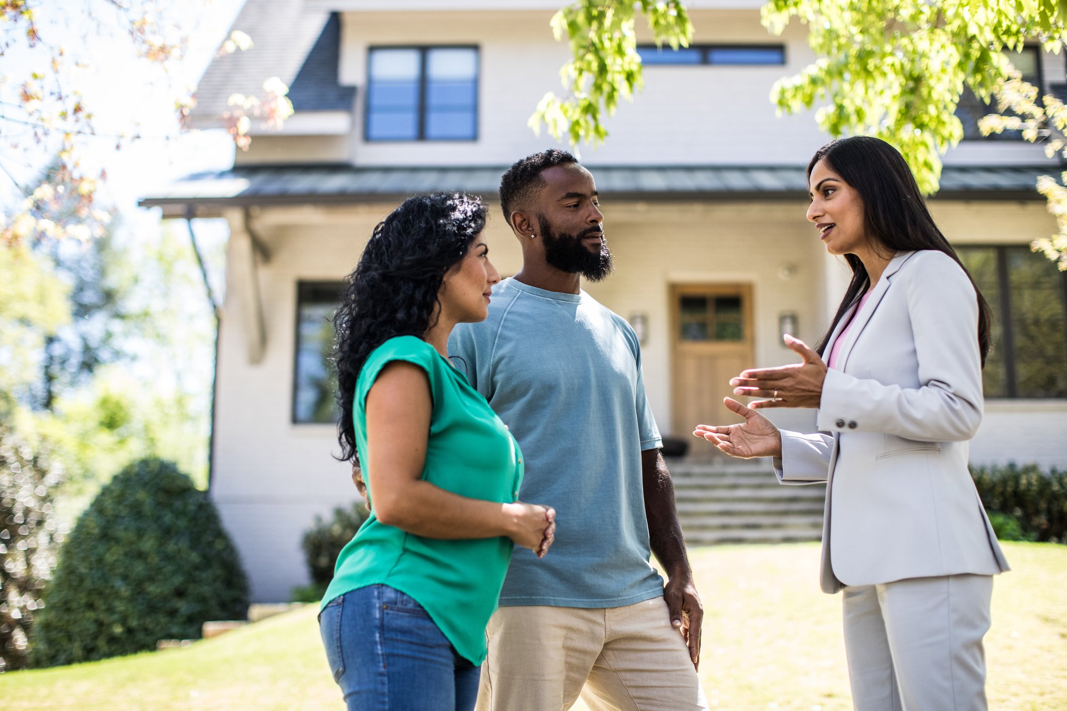 Couple in front of house with real estate agent.