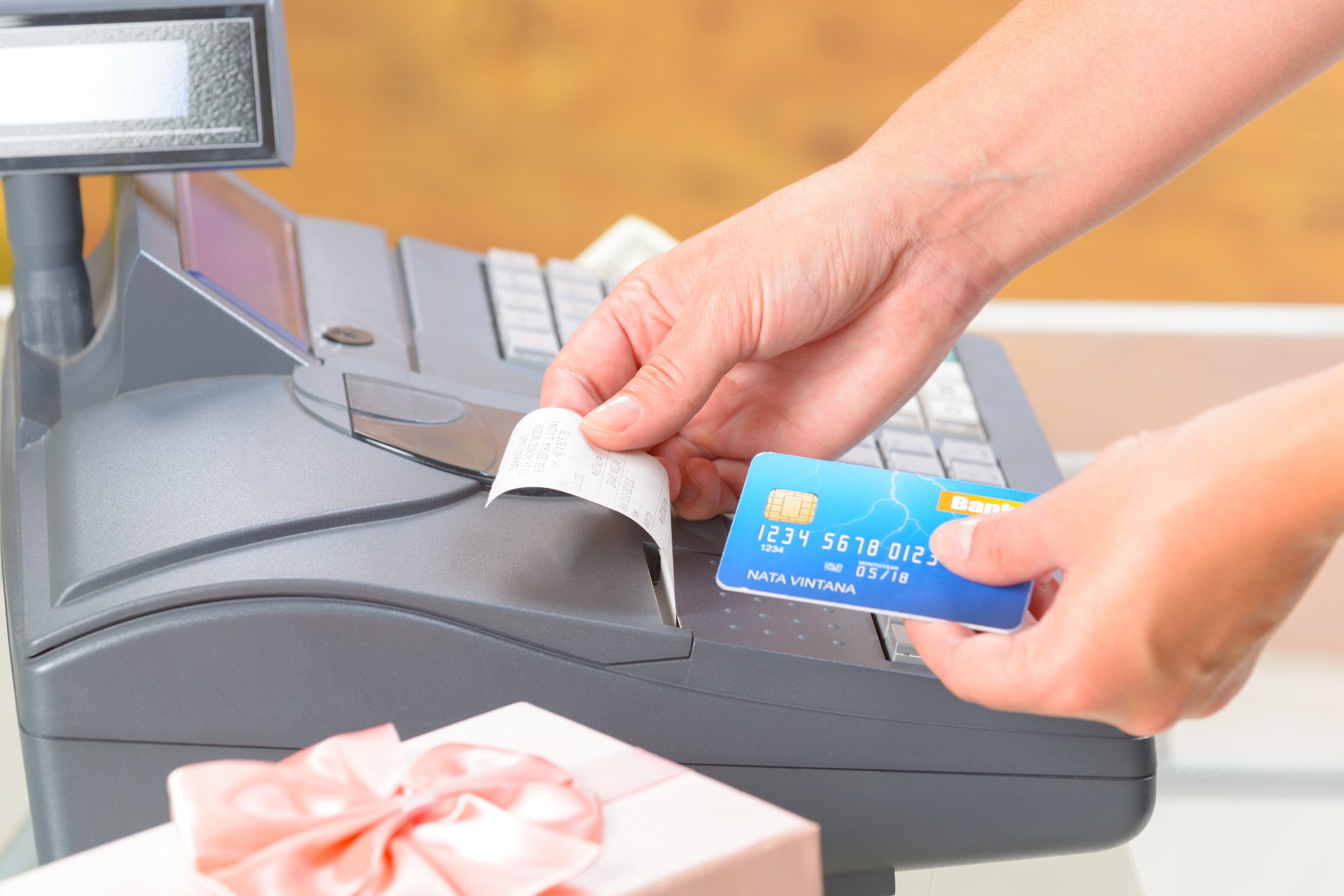 Cashier holding a credit card and a receipt.