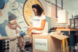 Charity volunteer assisting a client near donation box