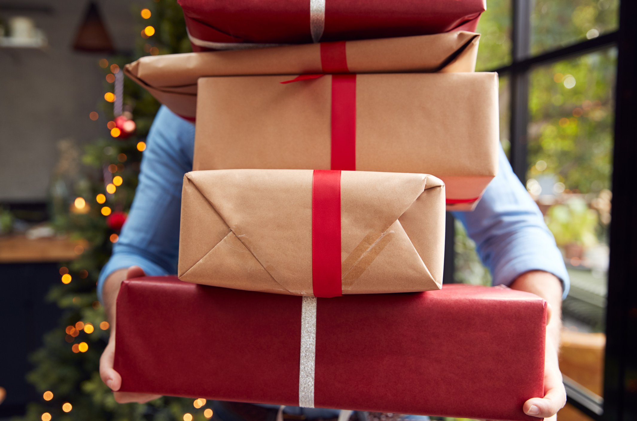 Person carrying large stack of Christmas gift boxes